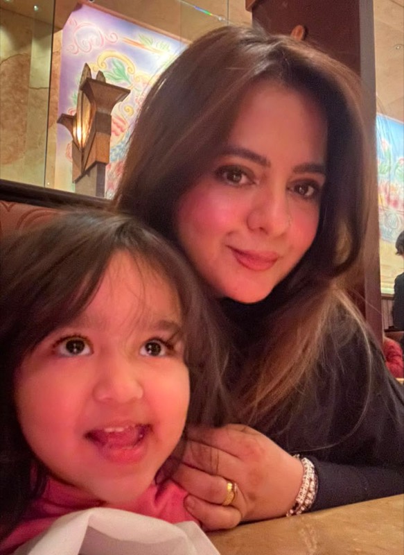 Ainza Huda, the Little Hearts Home Daycare caregiver, smiling with a happy little one
